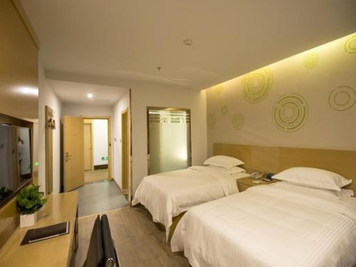 a hotel room with two beds and a television at GreenTree Inn Zhenjiang Danyang City Danbei Town Xinqiao Business Hotel in Matunlijia