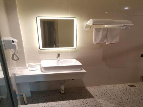 a bathroom with a sink and a mirror and towels at Shell Liaocheng Linqing City Bus Station Hotel in Liaocheng