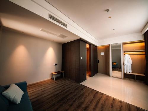 a living room with a blue couch and a bedroom at GYA hotel Linyi Lanshan Hailian International Plaza in Linyi