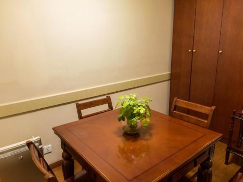 a wooden table with a vase of flowers on it at GreenTree Inn Jiangsu Taizhou Jingjiang Bus Station Express Hotel in Jingjiang