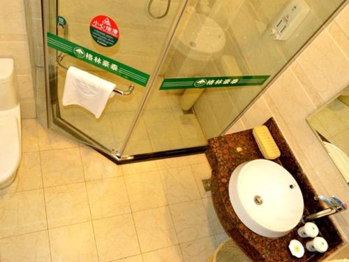 a bathroom with a sink and a toilet in a stall at GreenTree Inn Shandong Qingdao Jiaozhou Bus Terminal Station Hai'er Avenue Express Hotel in Jiaozhou