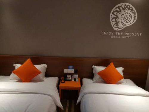 two beds with orange pillows in a hotel room at Shell Liaocheng Linqing City Bus Station Hotel in Liaocheng