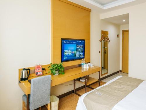 a room with a desk with a tv on it at GreenTree Inn Jiangyin Bus Station Meiyuan Street Express Hotel in Wuxi