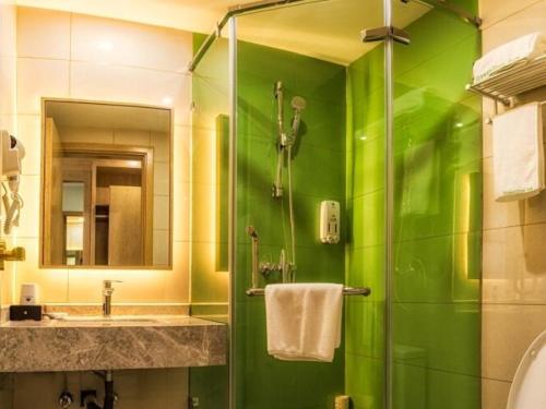 a green bathroom with a sink and a shower at GreenTree Inn Tangshan Road North District Xishan Road Business Hotel in Tangshan