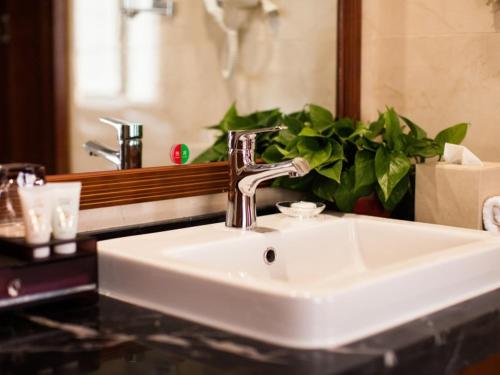 a white sink in a bathroom with a mirror at GreenTree Eastern Bozhou Jingwan Wealth Centre Hotel in Bozhou