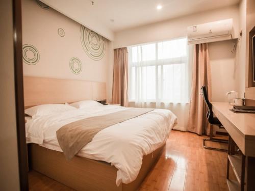 une chambre avec un lit, un bureau et une fenêtre dans l'établissement GreenTree Inn Heze Yucheng County Dongcheng International Business Hotel, à Yuncheng