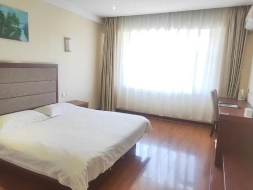 a bedroom with a large white bed and a window at GreenTree Inn Jilin Changchun Haoyue Road Express Hotel in Changchun