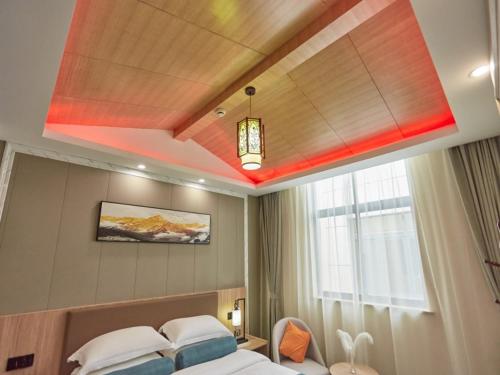 a hotel room with a bed and a window at GreenTree Inn Huangshan TangKou Beauty Spot South Gate Transfer Center Business Hotel in Huangshan Scenic Area