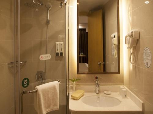 a bathroom with a sink and a shower with a mirror at GreenTree Inn Bengbu Longzihu District Railway Station Express Hotel in Bengbu