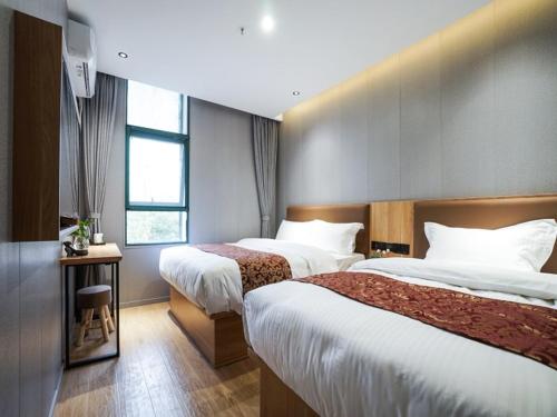 a hotel room with two beds and a window at Green Alliance Baoshan Shanghai University Qihua Road Metro Station in Shanghai