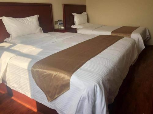 two beds in a hotel room with white sheets at GreenTree Inn Shanxi Xinzhou South Jianshe Road Express Hotel in Xinzhou