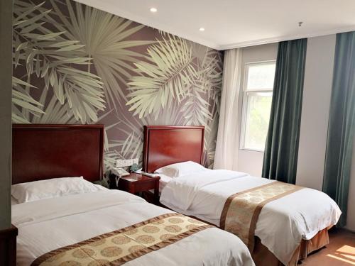 a bedroom with two beds and a palmrative wall at GreenTree Inn Zhejiang Ningbo Dongqian Lake Yinxian Avenue North Mozhi Road Business Hotel in Ningbo