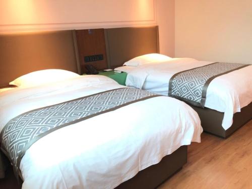 two beds in a hotel room with white sheets at GMA Hotel ShangHai WuNing Road ZhenPing Road Metro Station in Shanghai