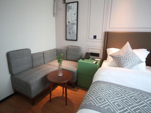 a bedroom with a bed and a couch and a table at GMA Hotel ShangHai WuNing Road ZhenPing Road Metro Station in Shanghai