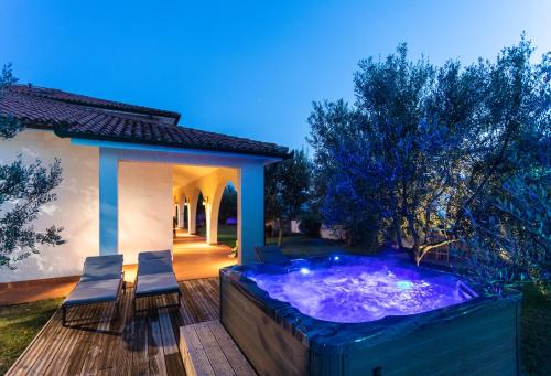 a hot tub on a deck with chairs and a house at Villa EMI in Zgornje Škofije