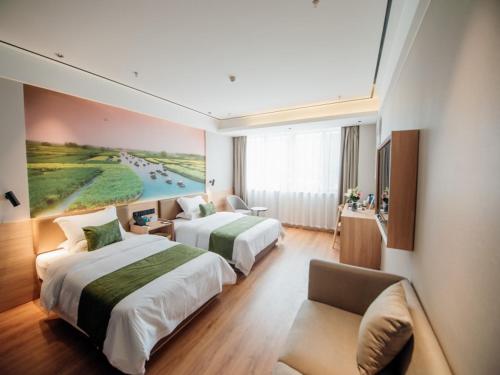ein Hotelzimmer mit zwei Betten und einer Couch in der Unterkunft GreenTree Inn Taizhou Xinghua City Zhouzhuang Town Business Hotel in Taizhou