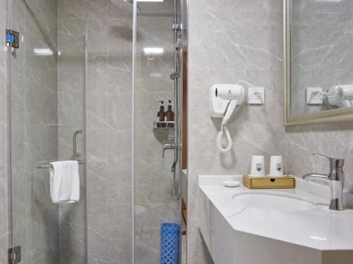 La salle de bains est pourvue d'une douche, d'un lavabo et d'une douche en verre. dans l'établissement GreenTree Inn Nanjing Qinhuai District Xinjiekou Subway Station Express Hotel, à Nankin