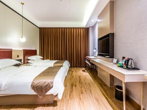 een hotelkamer met een groot bed en een bureau bij Gya Hangzhou Linan Qingshan Lake Science City Hotel in Hangzhou