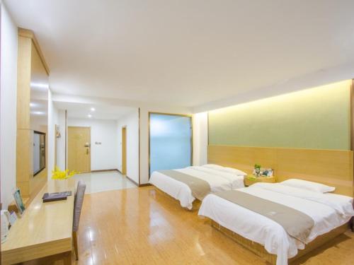 a bedroom with two beds and a desk at GreenTree Inn Xingxincheng Town Jiayuan Central Plaza Business Hotel in Jiaxing