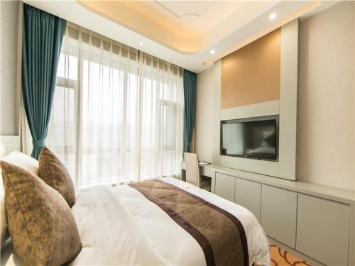 a bedroom with a large bed and a television at GreenTree Eastern Yibin Yijian Road New City Plaza Hotel in Baixi