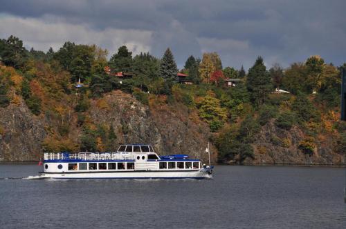a white boat on the water near a mountain at Hotel VZ Měřín in Merin