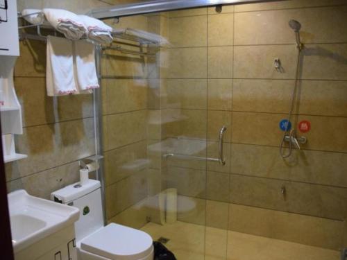 a bathroom with a shower with a toilet and a sink at Shell Fuzhou Nancheng County Railway Station Shengli West Road Hotel in Nancheng