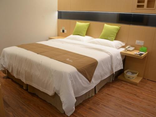 a bedroom with a large bed with green pillows at Vatica Xuzhou Suining Bus Station Bayi West Road Hotel in Suining