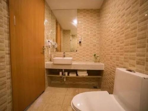 a bathroom with a sink and a toilet and a tub at Shell Yantai Mouping District Gongshang Dajie Hotel in Yantai
