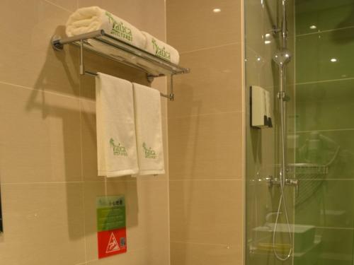 a bathroom with a shower and white towels at Vatica Xuzhou Suining Bus Station Bayi West Road Hotel in Suining