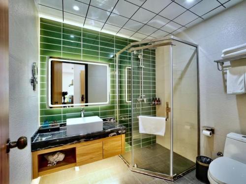ein grün gefliestes Bad mit einem Waschbecken und einer Dusche in der Unterkunft GreenTree Inn Changzhou Xuebu Eastern Salt Lake City in Changzhou