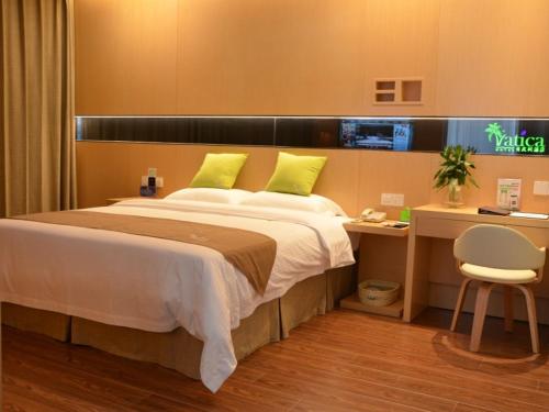 a bedroom with a large bed with a desk and a chair at Vatica Xuzhou Suining Bus Station Bayi West Road Hotel in Suining