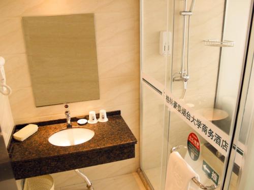 a bathroom with a sink and a shower at GreenTree Inn ShanDong Yantai Yantai University Business Hotel in Yantai