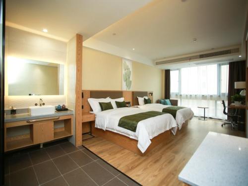a bedroom with a bed and a sink and a tub at GreenTree Inn Huai'an High-speed Railway Station University City East Yan'an Road in Huai'an