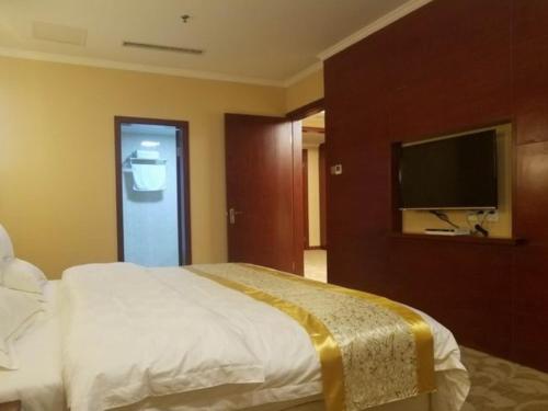 a bedroom with a bed and a flat screen tv at GreenTree Alliance Suzhou Taicang South Changchun Road Liuyuan Hotel in Taicang