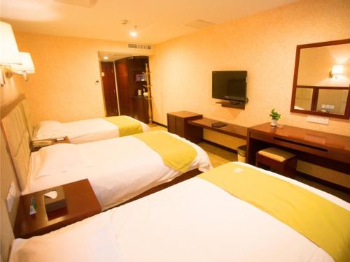 a hotel room with two beds and a desk with a television at GreenTree Alliance Nanping Yanping District Xinjian Road Hotel in Nanping