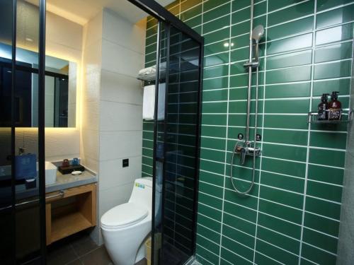 a green tiled bathroom with a toilet and a shower at GreenTree Inn Huai'an High-speed Railway Station University City East Yan'an Road in Huai'an