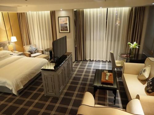 Habitación de hotel con cama, TV y sofá en GreenTree Inn Guangdong Shantou Chengjiang Road Business Hotel, en Shantou