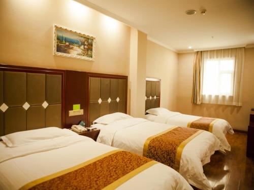 a hotel room with three beds and a window at GreenTree Inn Shanxi Taiyuan Jianshe S) Road Inner Ring Express Hotel in Taiyuan