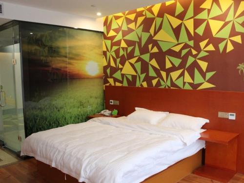 a bedroom with a large bed with a painting on the wall at Vatica Fuyang Linquan County Tenghui International City Hotel in Fuyang