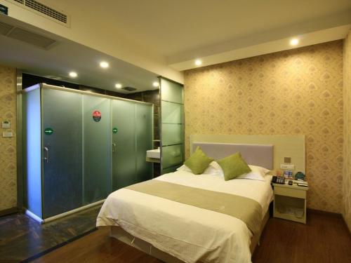 a bedroom with a large bed and a glass shower at GreenTree Inn WenZhou LuCheng XiaoNanMen Express Hotel in Wenzhou