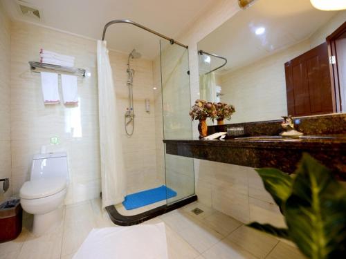 a bathroom with a shower and a toilet and a sink at Shell Yantaishan Park Hotel in Yantai