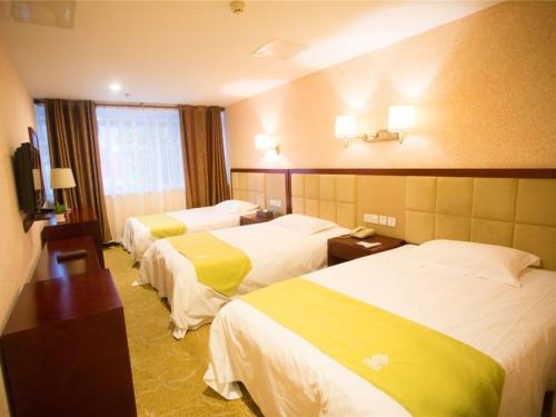 a hotel room with three beds with yellow sheets at GreenTree Alliance Nanping Yanping District Xinjian Road Hotel in Nanping