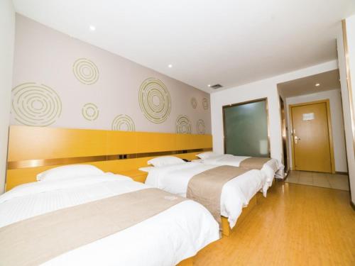 a group of four beds in a room at GreenTree Inn Suzhou Zhangjiagang City Jingang Town Express Hotel in Zhangjiagang