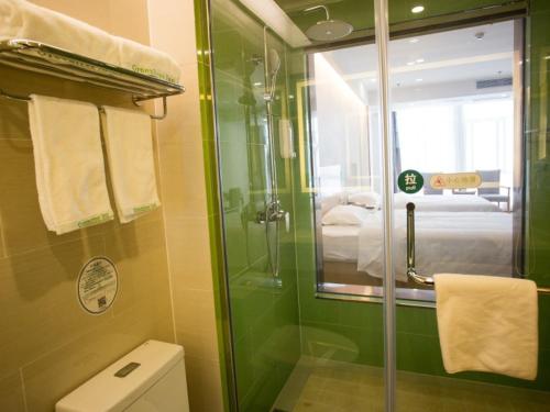 a green bathroom with a shower and a toilet at GreenTree Inn Suzhou Yongqiao District Fuxiao Avenue Hotel in Suzhou