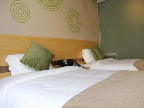 a hotel room with two beds with green pillows at GreenTree Inn Langfang Dachang Movie City Select Hotel in Dachang