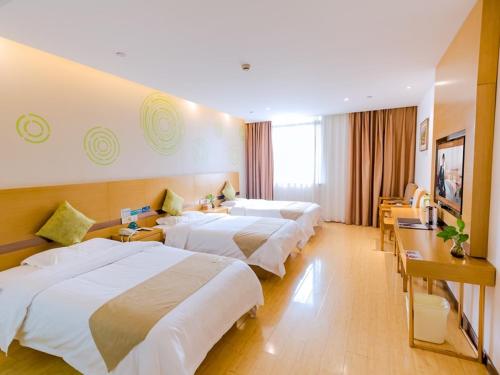a hotel room with three beds and a television at GreenTree Inn Huzhou Zhili Fortune Plaza Wuxing Avenue Express Hotel in Huzhou