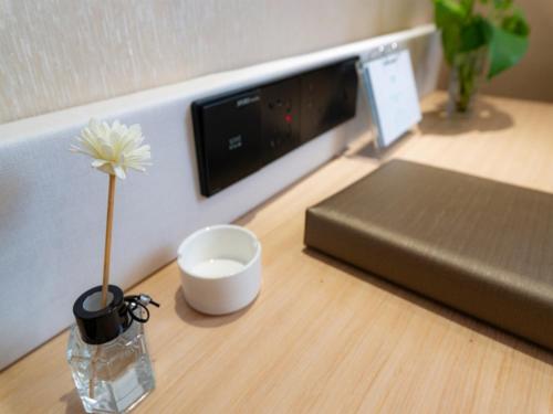 a flower in a vase sitting on a desk at VX Xuzhou Yunlong District Normal University Yunlong Mountain Scenic Spot Hotel in Xuzhou