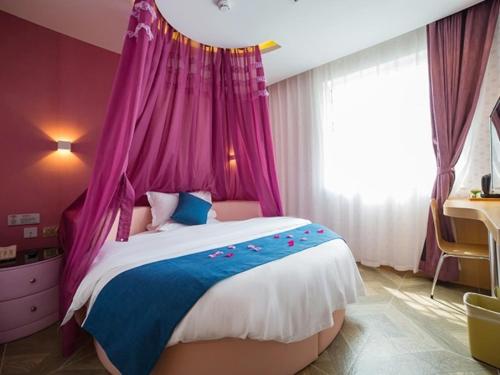 a bedroom with a bed with a pink canopy at Shell Yantai Mouping District Gongshang Dajie Hotel in Yantai