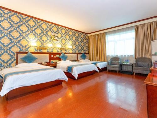 a hotel room with two beds and a chair at GreenTree Inn Nanning Xiuxiang Branch in Nanning