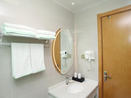 a bathroom with a sink and a mirror and towels at GreenTree Inn Hefei Huainan Road Huaihe Garden Express Hotel in Hefei